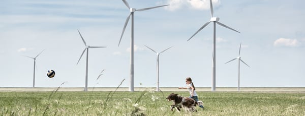 Flicka med hund vid vindkraftverk